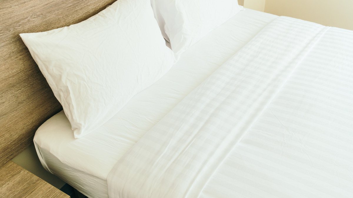 Gros plan sur le linge de lit parfaitement repassé et posé. 